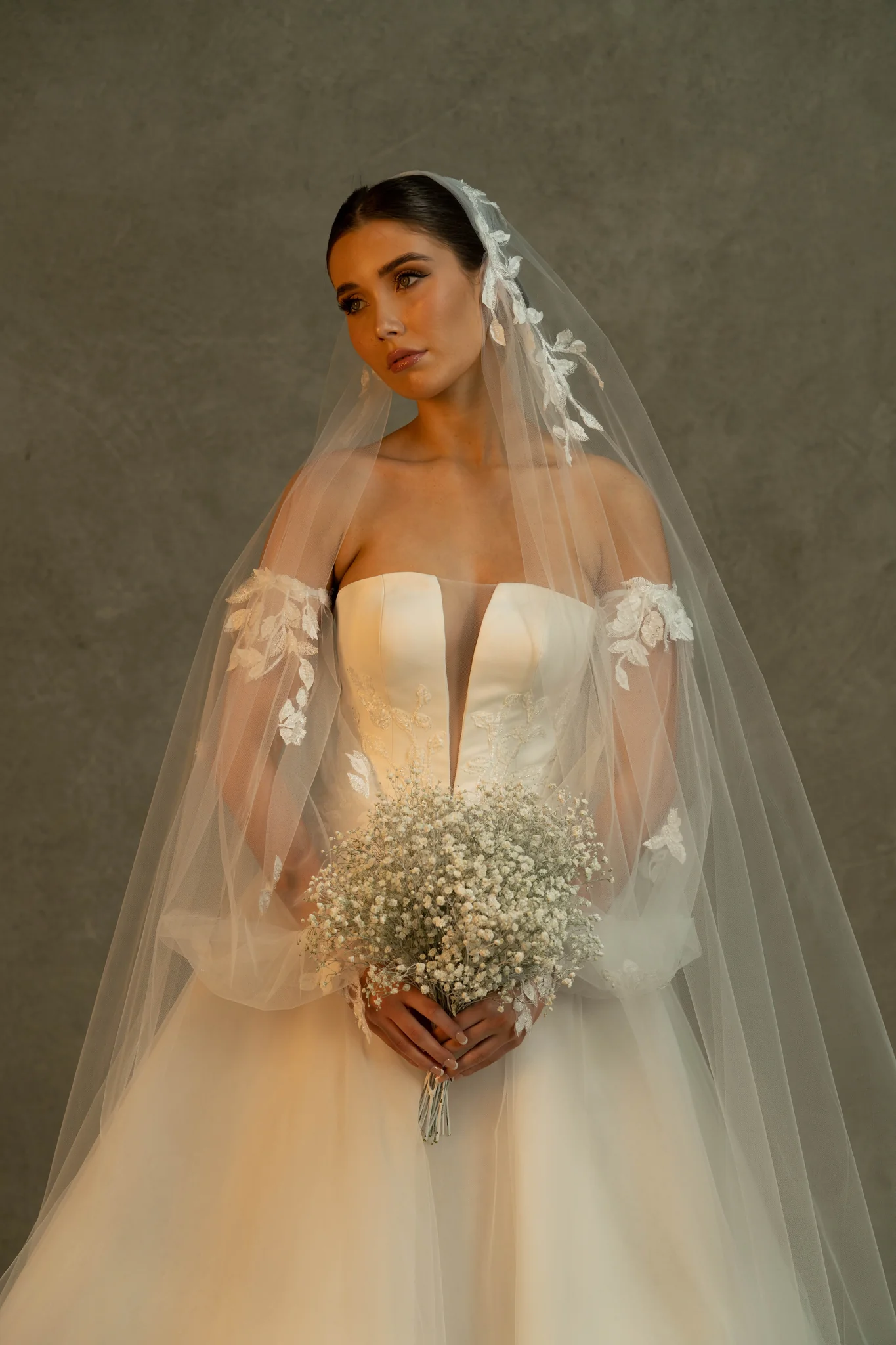 A Fara Couture bride in a couture gown and veil holding a bouquet